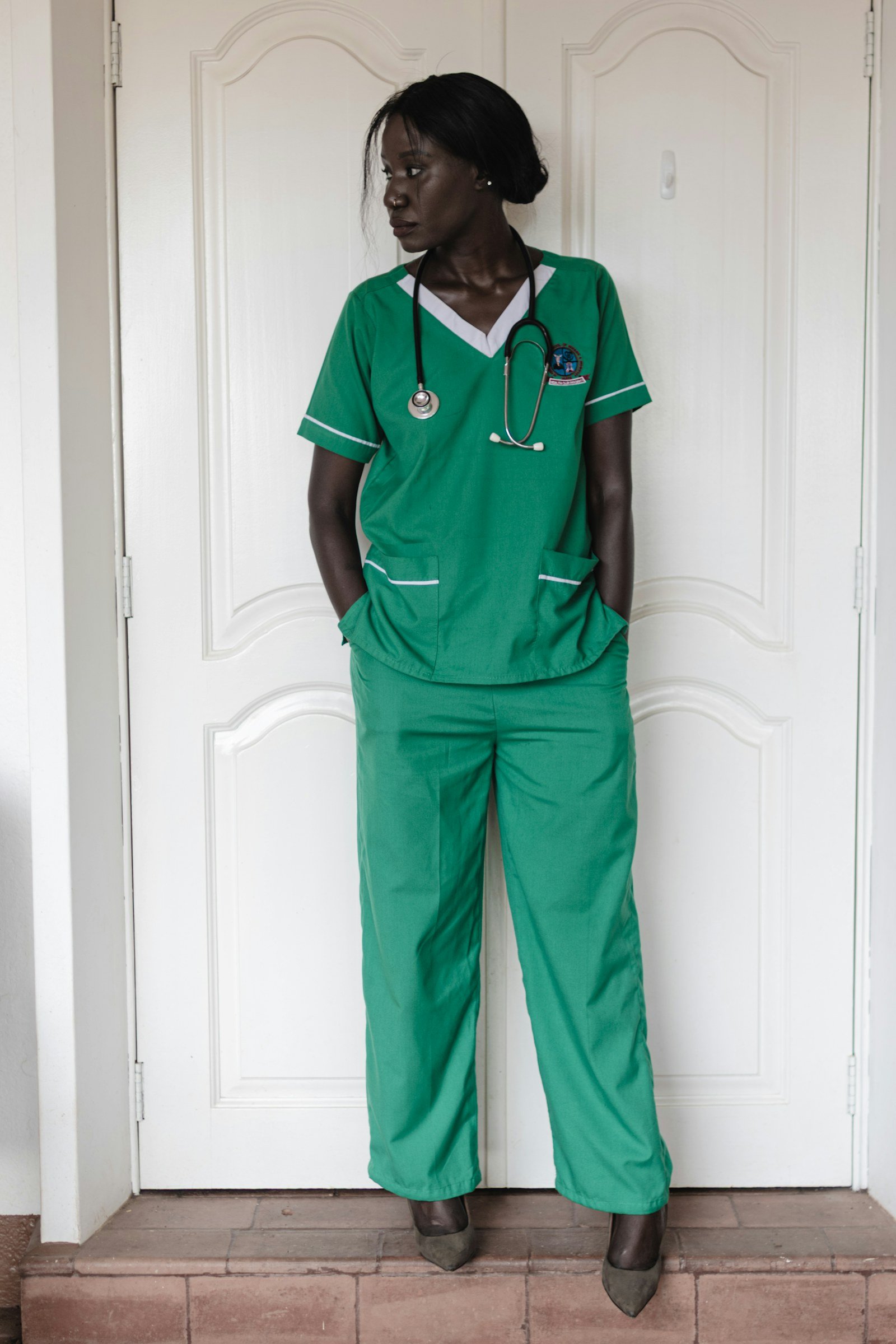 A nurse in green scrubs standing in Kampala, Uganda